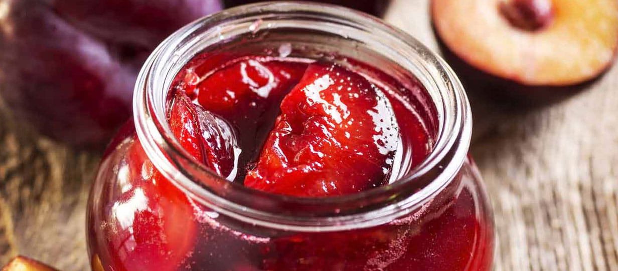 Open jar of spiced pickled plums