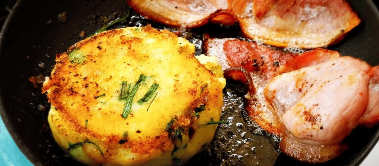 a potato cake and rashers of bacon in a frying pan