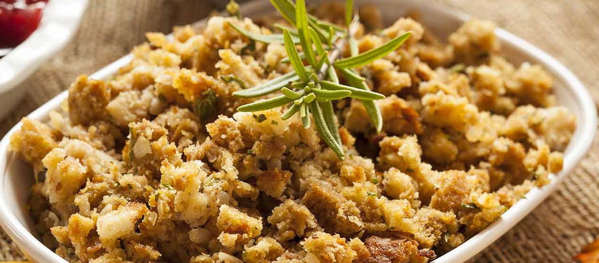 White dish filled with pork chestnut stuffing topped with a sprig of rosemary