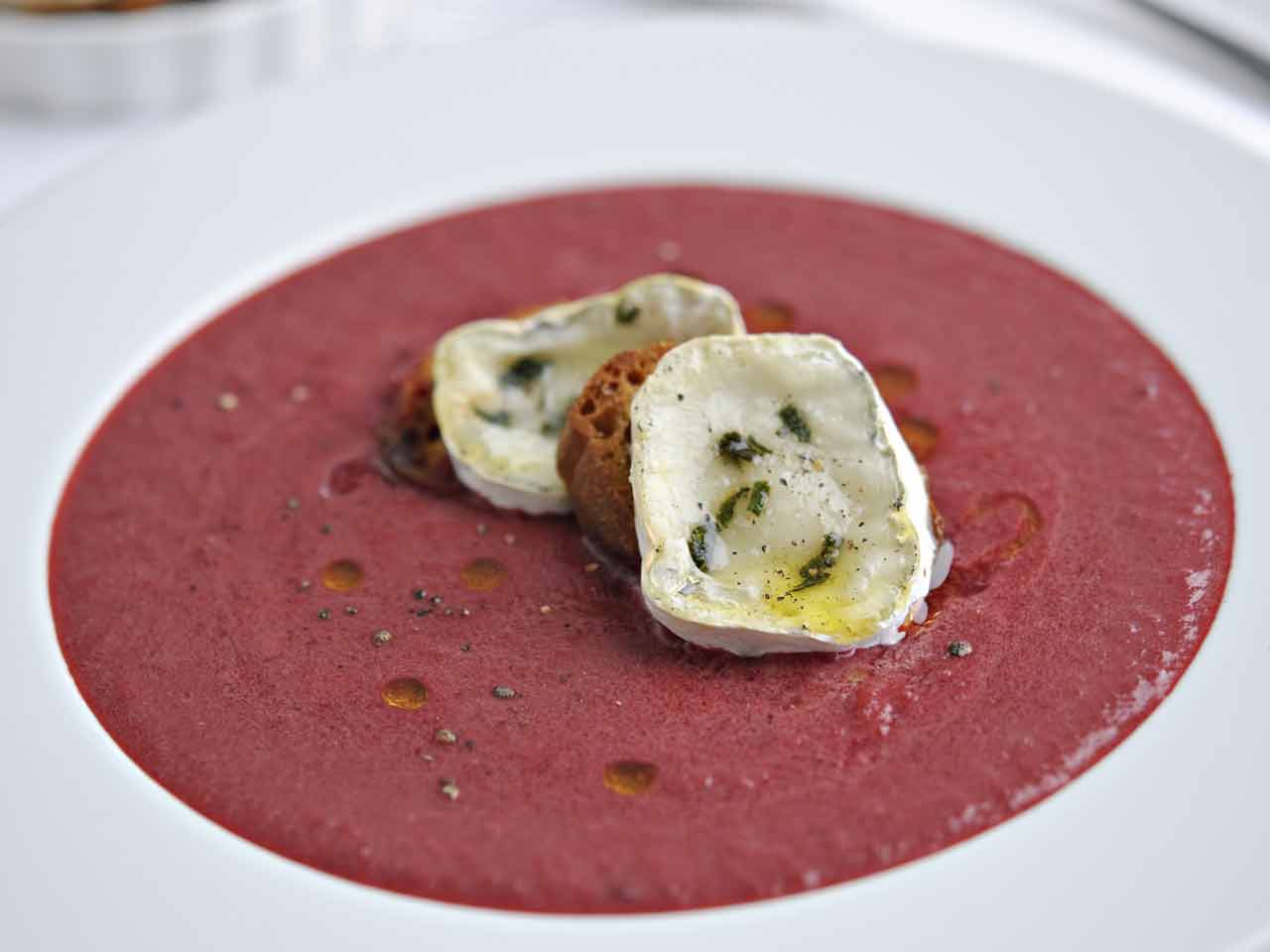Bowl of beetroot soup topped with croutons and goats cheese