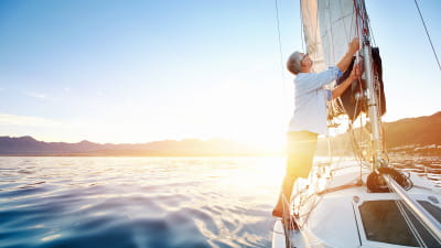 A man on his sailboat working the sails