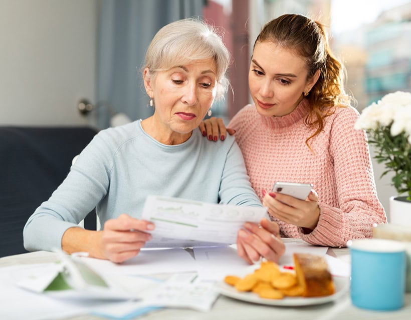 Mother and daughter sitting at table and calculating finances.