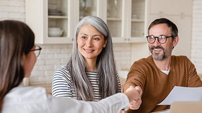 Happy mature middle-aged couple clients signing documents