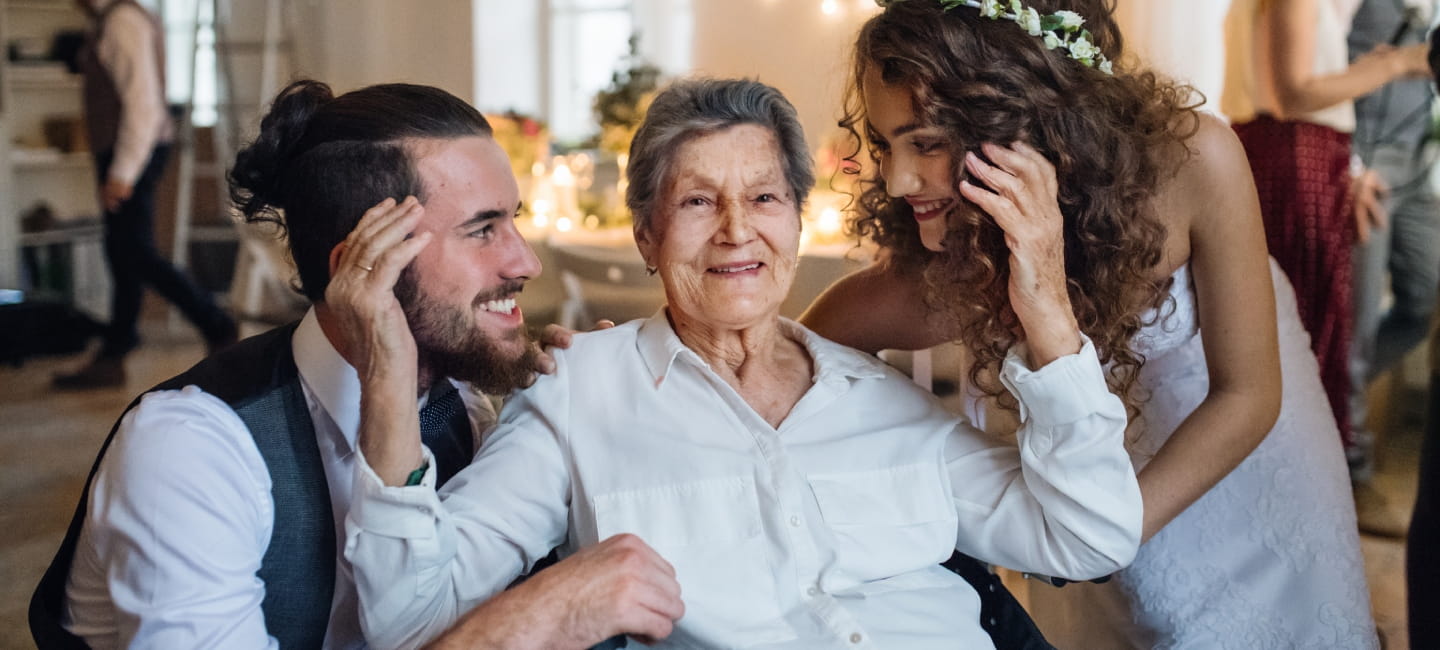 Bride and groom hugging grandmother at wedding 