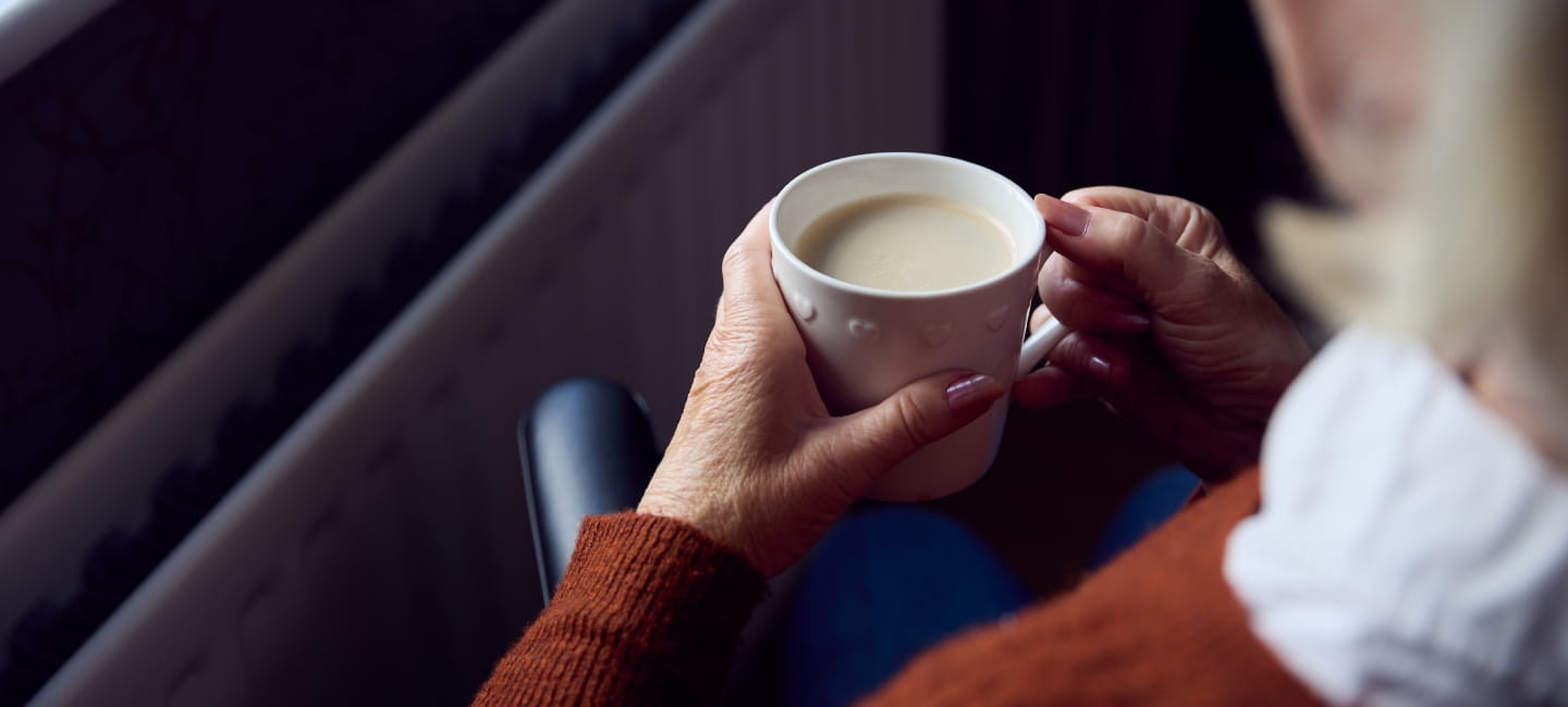 A person sat holding a cup of tea
