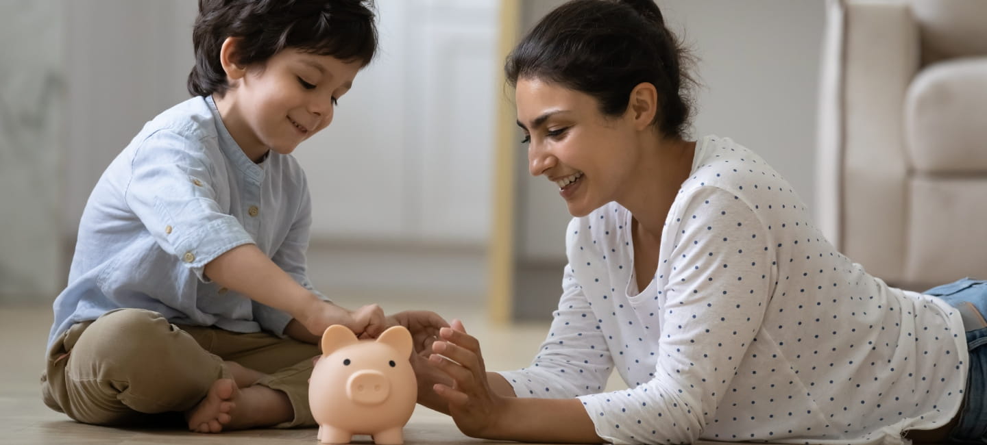 A mother and son adding money to a piggy bank