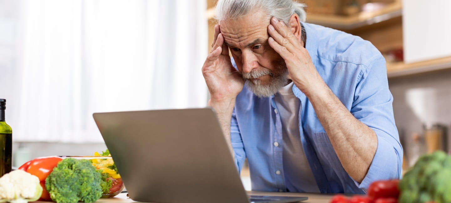 A man with his head in his hands staring at a laptop screen