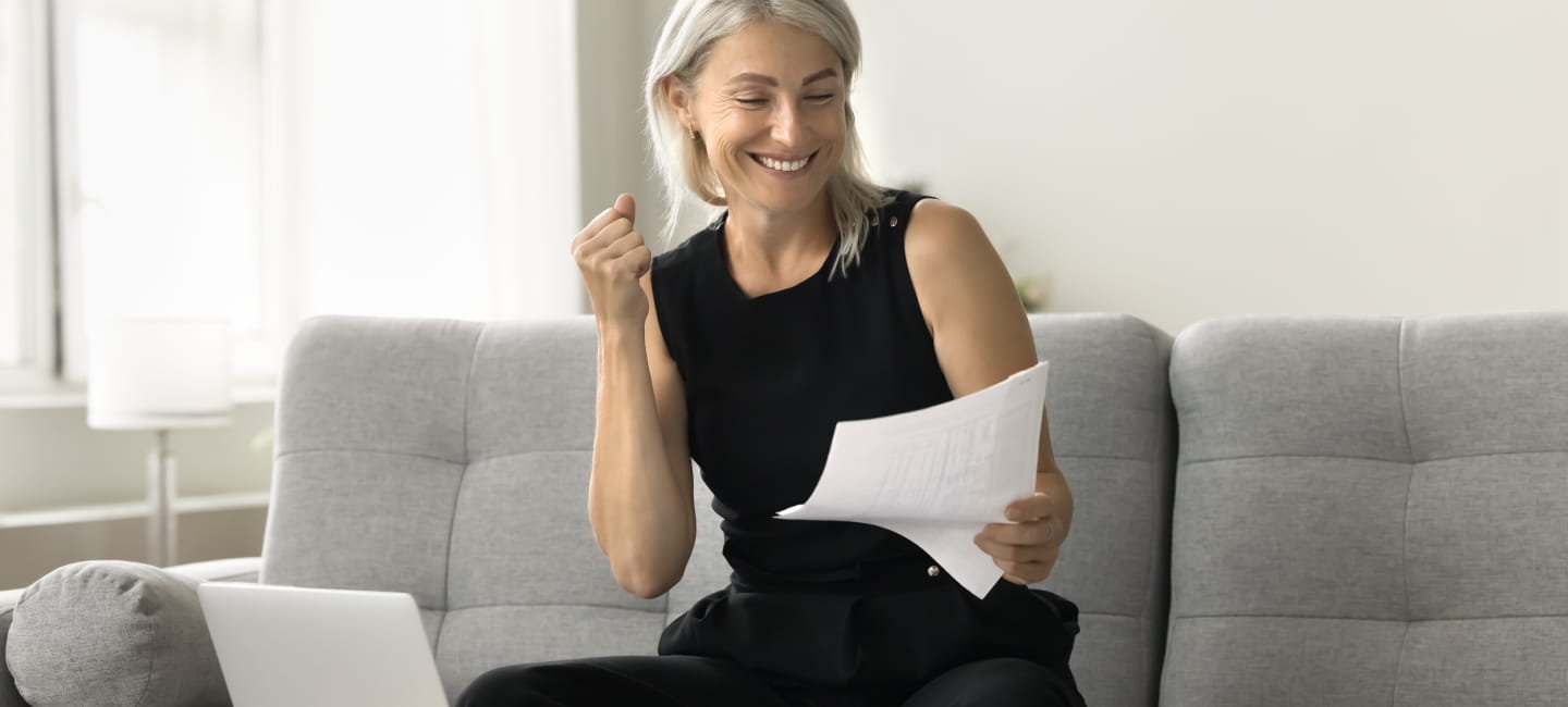 A woman sat on the sofa with paperwork in her hand. She is clearly happy!