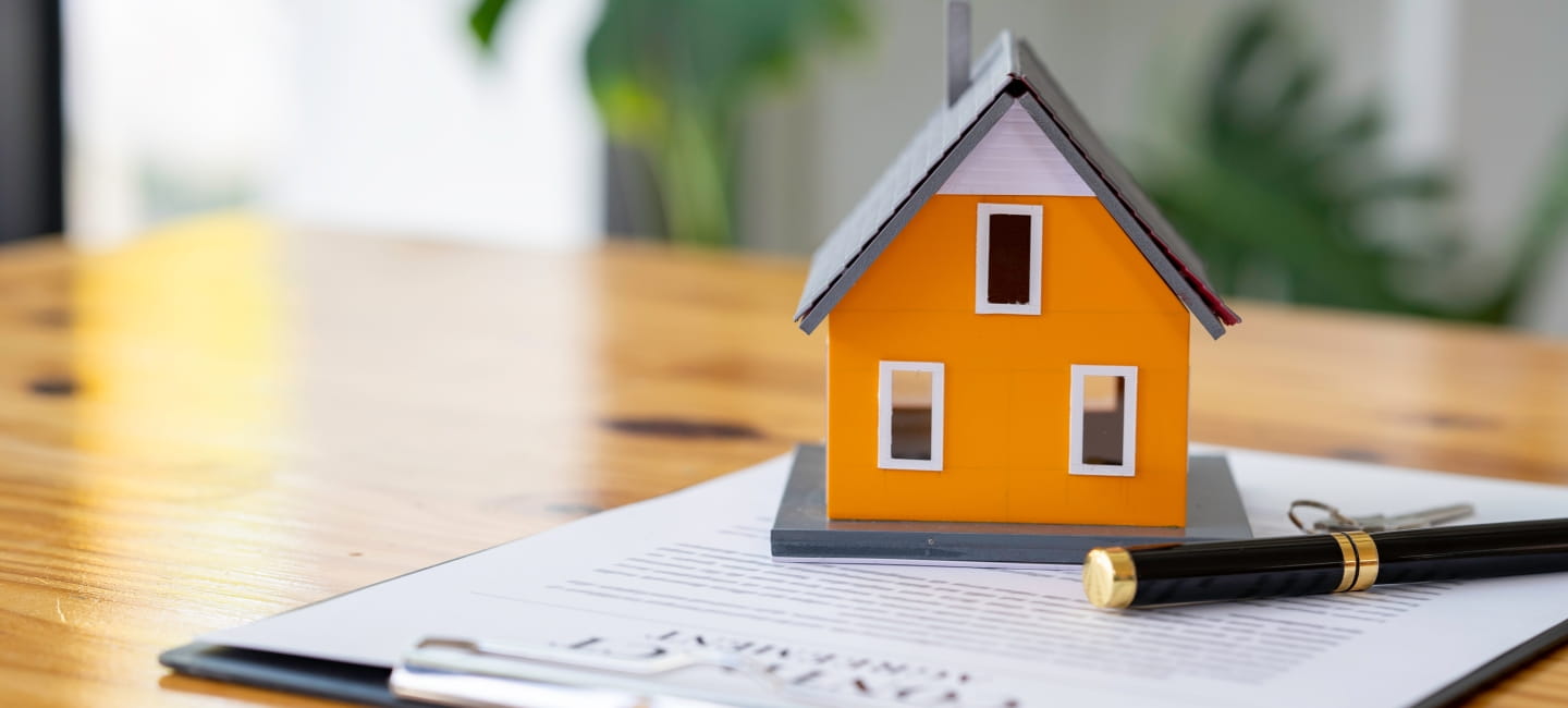 A miniature house sat on paper on a desk 