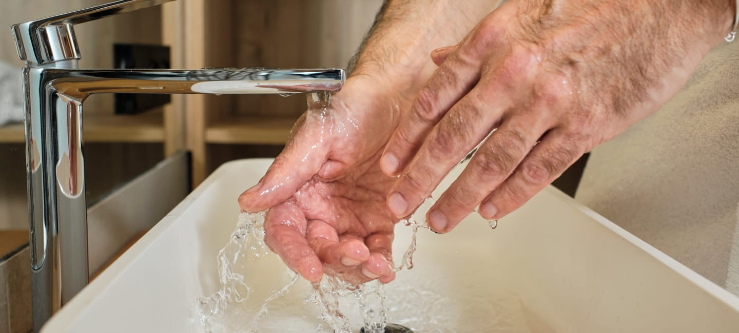 A man washing his hands under a tap