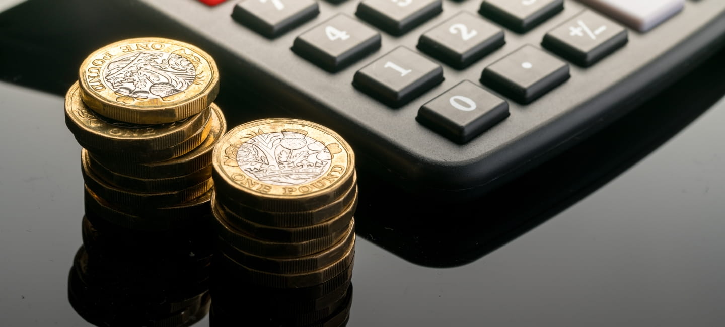 Pound coins stacked up next to a calculator