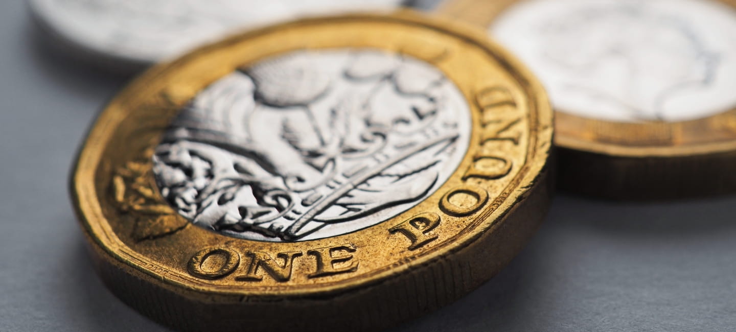 British money lies on gray surface. One coin close-up. Economy and money. Bank of England. UK currency and inflation. Pound horizontal stories. Macro