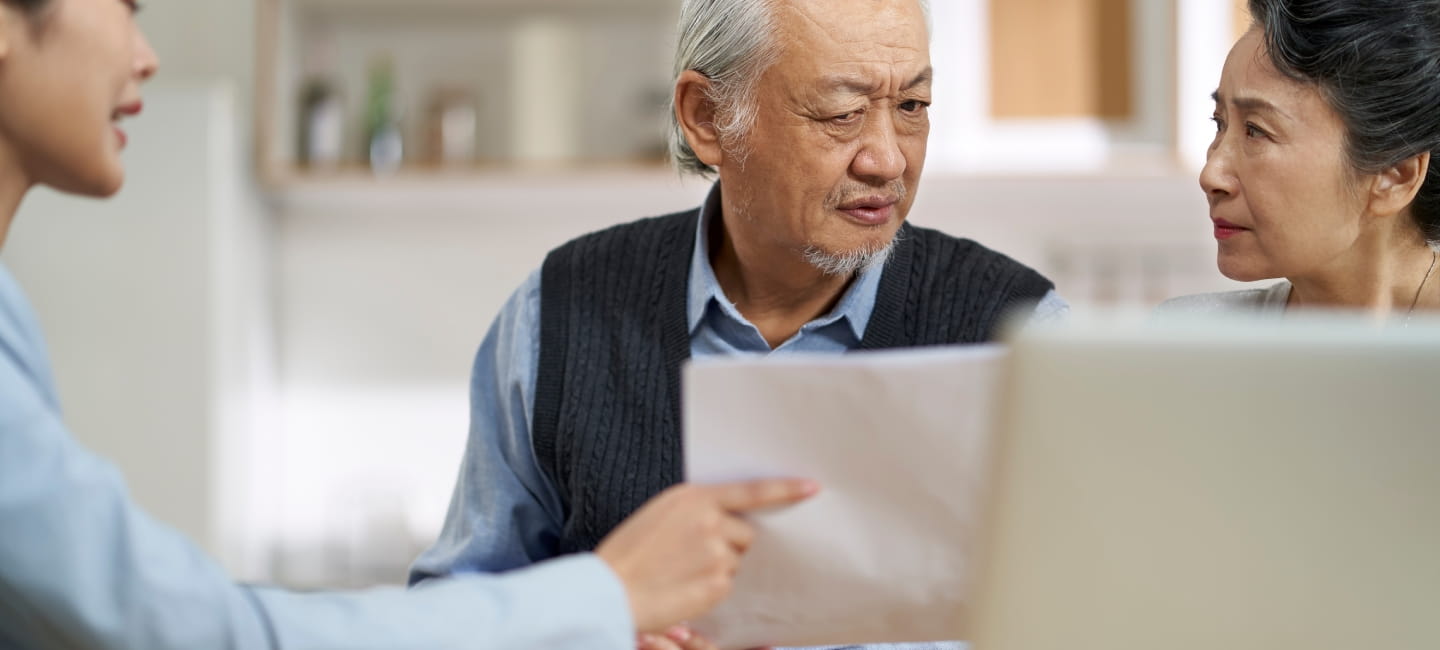 Senior asian couple appears confused by and suspicious at a sales person selling financial product