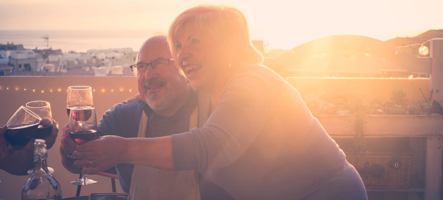 group of aged senior friends adults having dinner and doing party nice time in the rooftop terrace outdoor with wine and food. having fun during the sunset with beautiful sun backlight and amazing vie