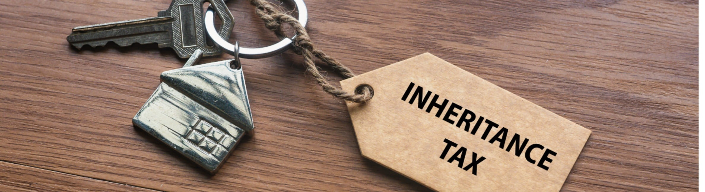 A house key with a tag written with Inheritance Tax on wooden background.