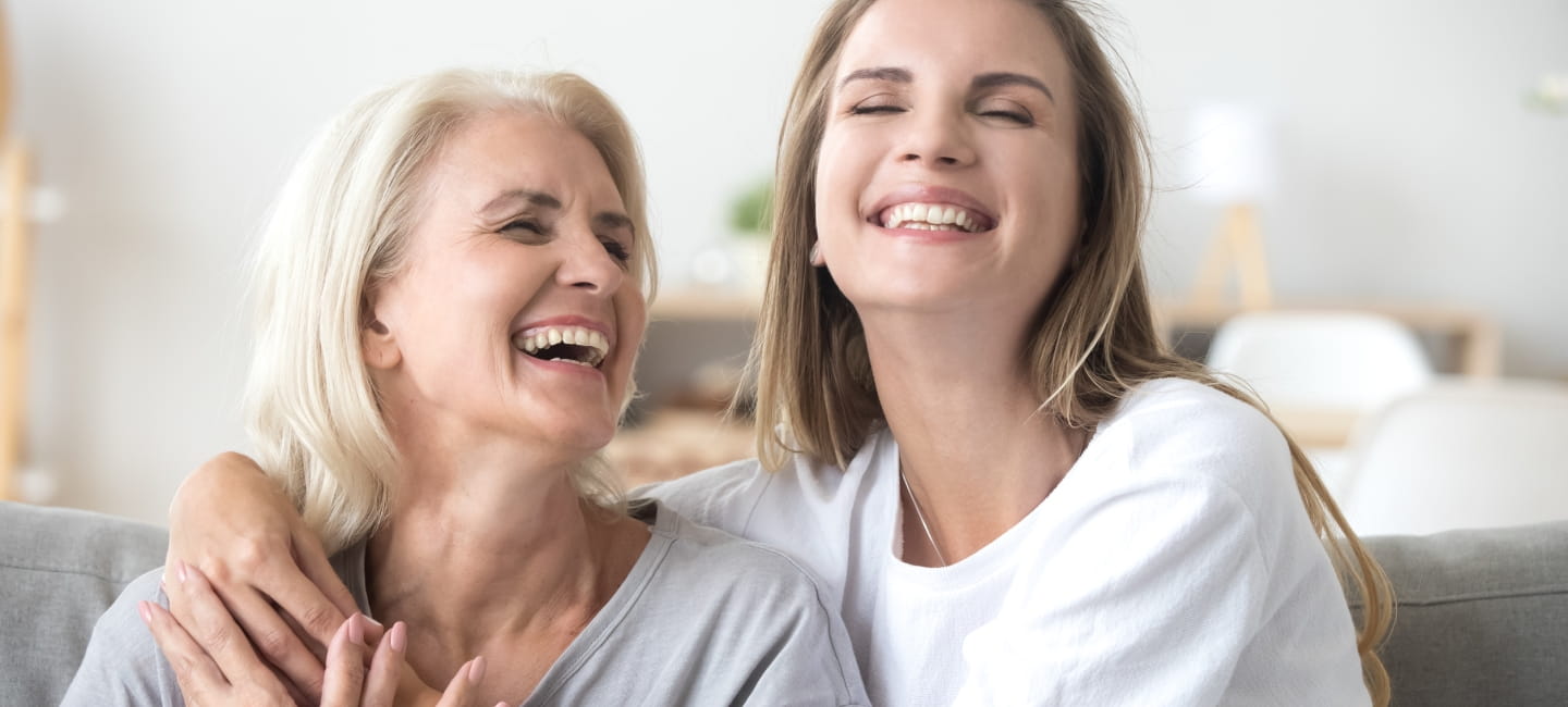 Happy senior mature mother embracing young adult woman laughing together, smiling elderly older mum joking having fun with grown daughter, two age generations humour and positive emotions concept.