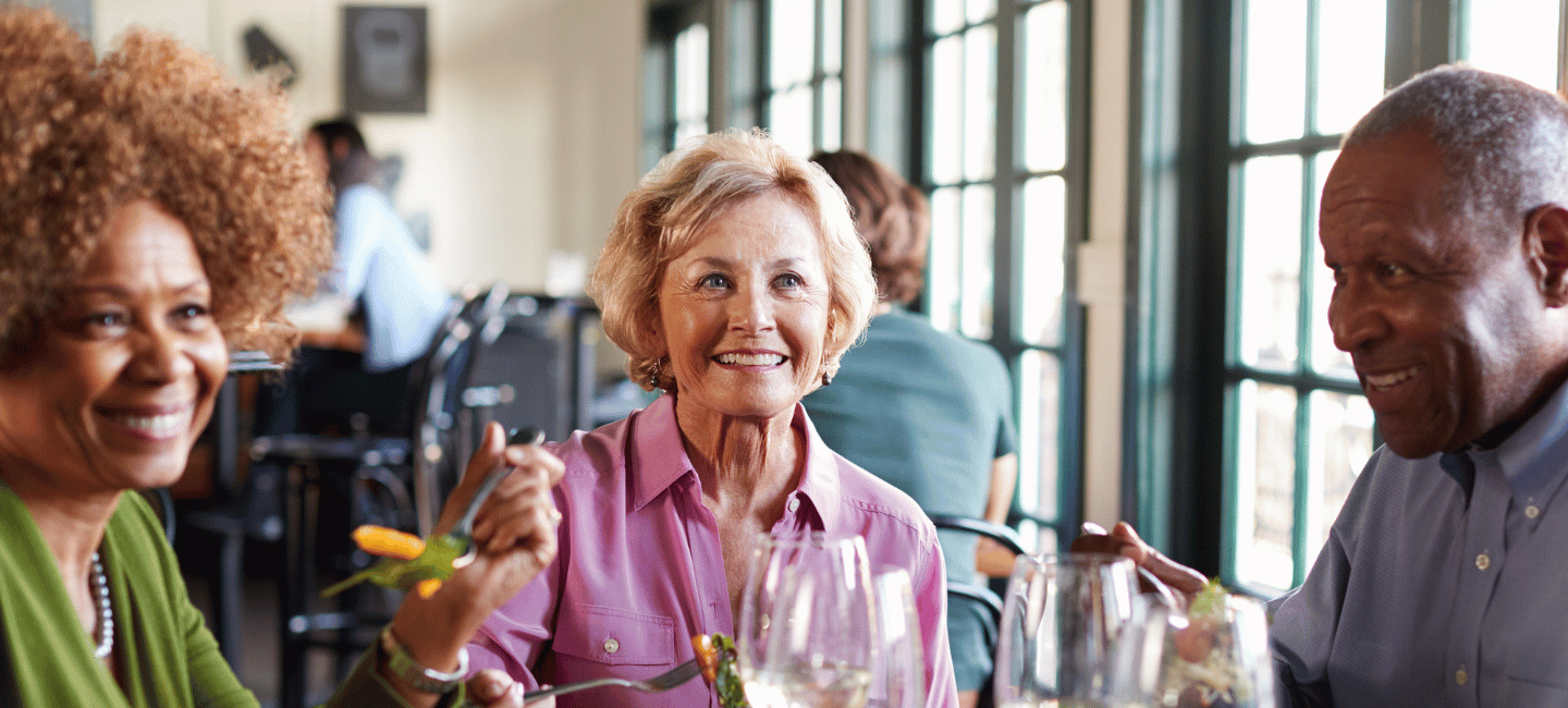 Group Of Smiling Senior Friends Meeting For Meal In Restaurant