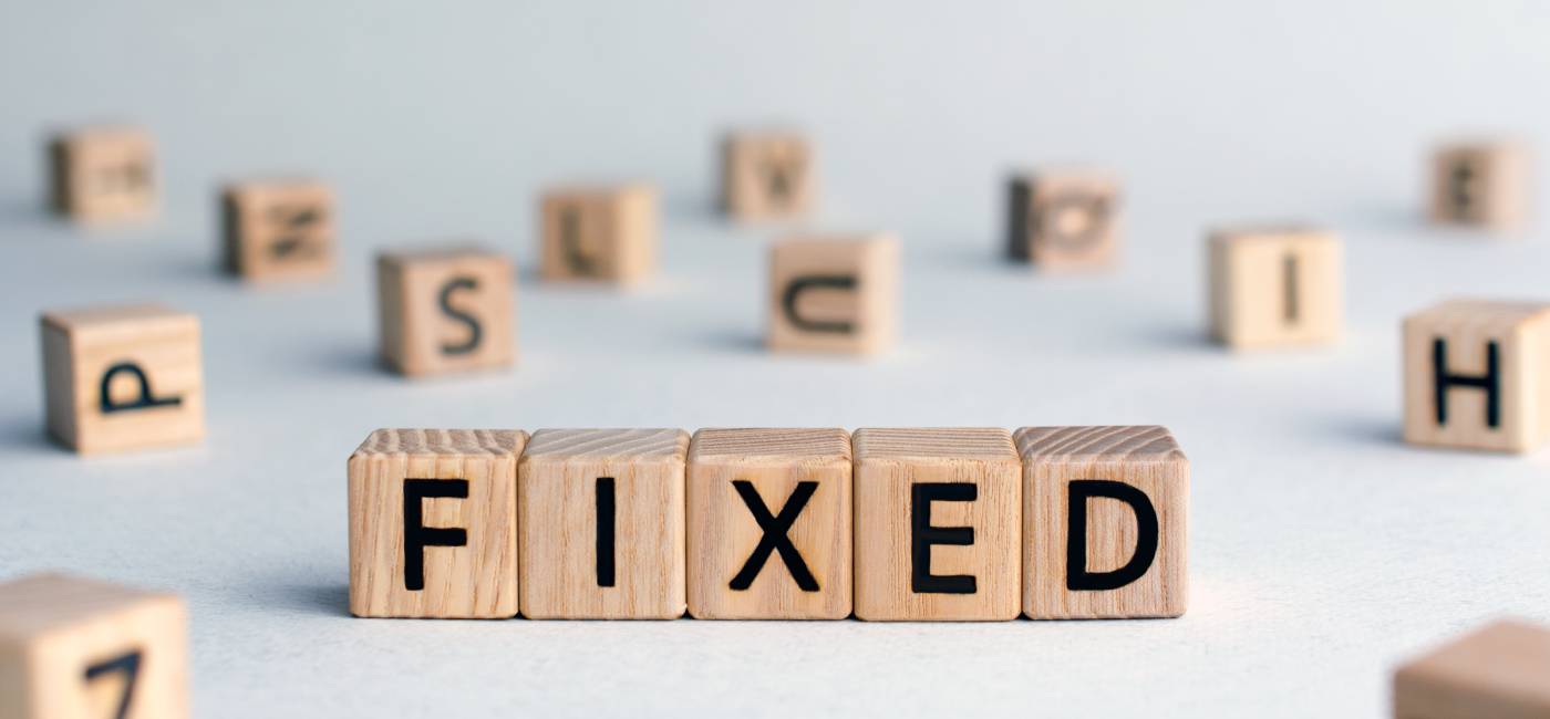 Fixed - word from wooden blocks with letters, fixed interest rates or costs  concept, random letters around, top view on wooden background