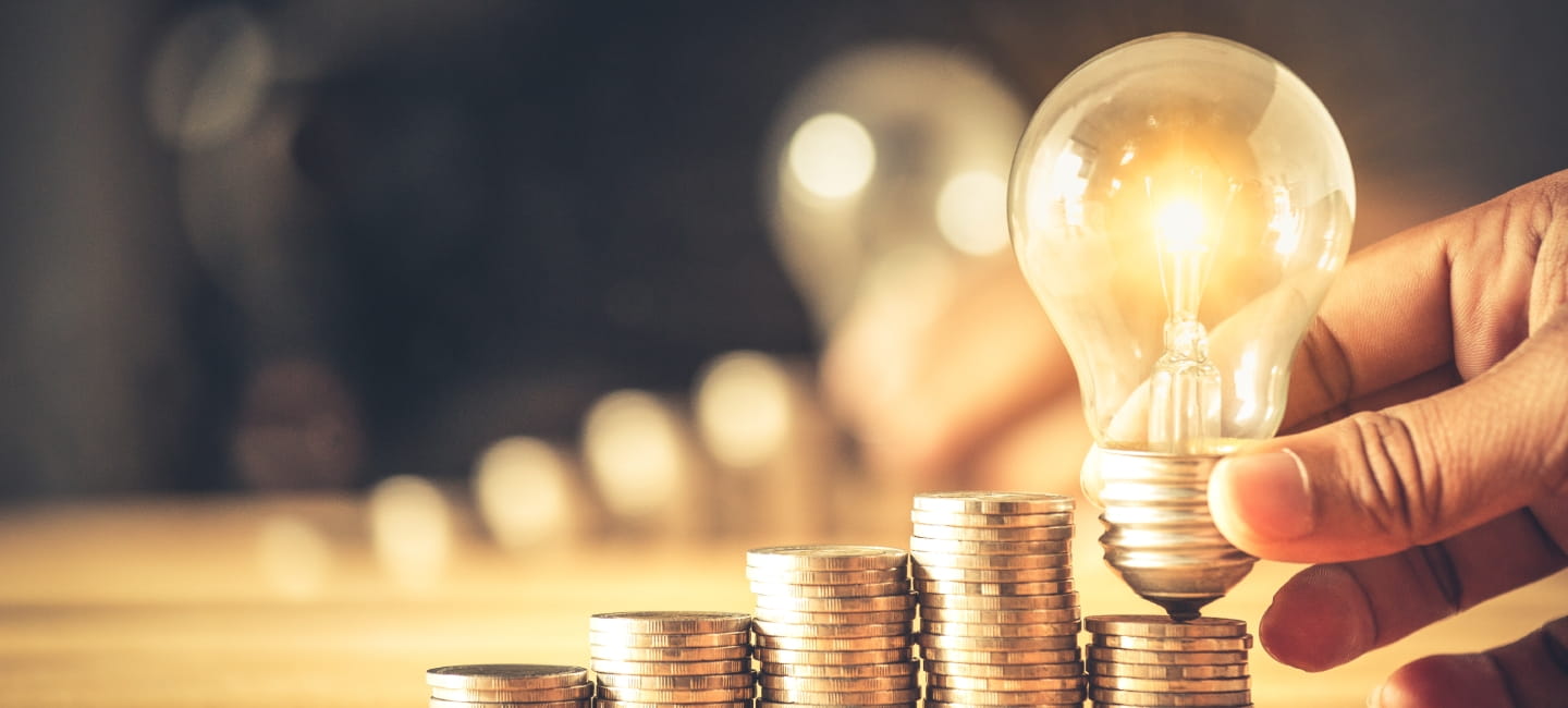 Hand holding a light bulb with coins stack. Creative ideas for saving money concept. Money management for the future.