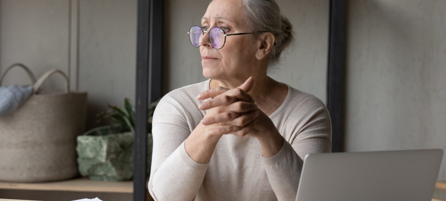Stressed pensive middle aged woman in eyeglasses looking in distance, thinking of financial problems, suffering from lack of money, feeling stressed analyzing domestic expenditures or planning budget.