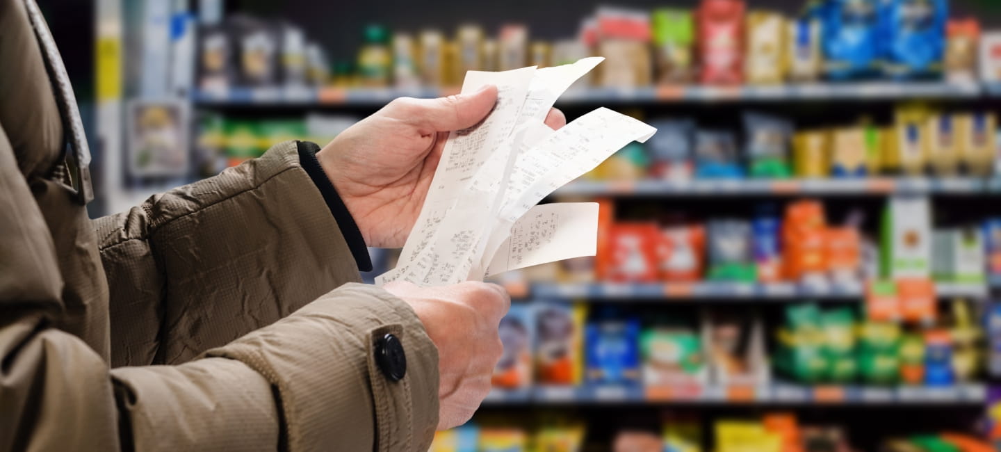 Minded man viewing receipts in supermarket and tracking prices.
