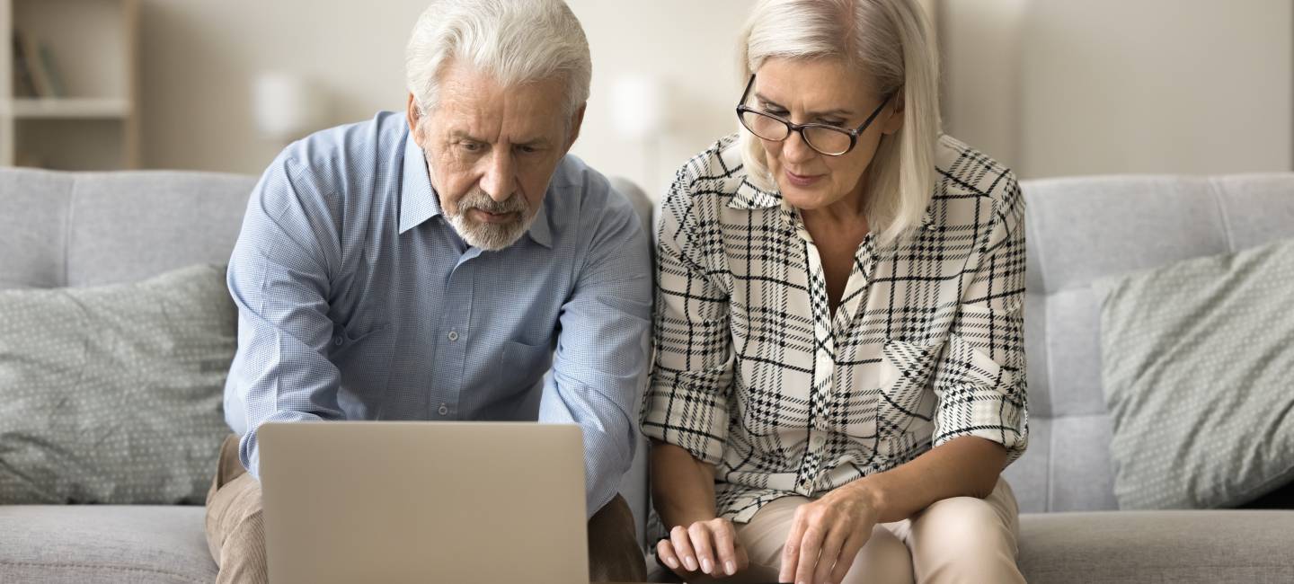 Mature couple sitting with a laptop, checking bills for payment, counting budget and  savings