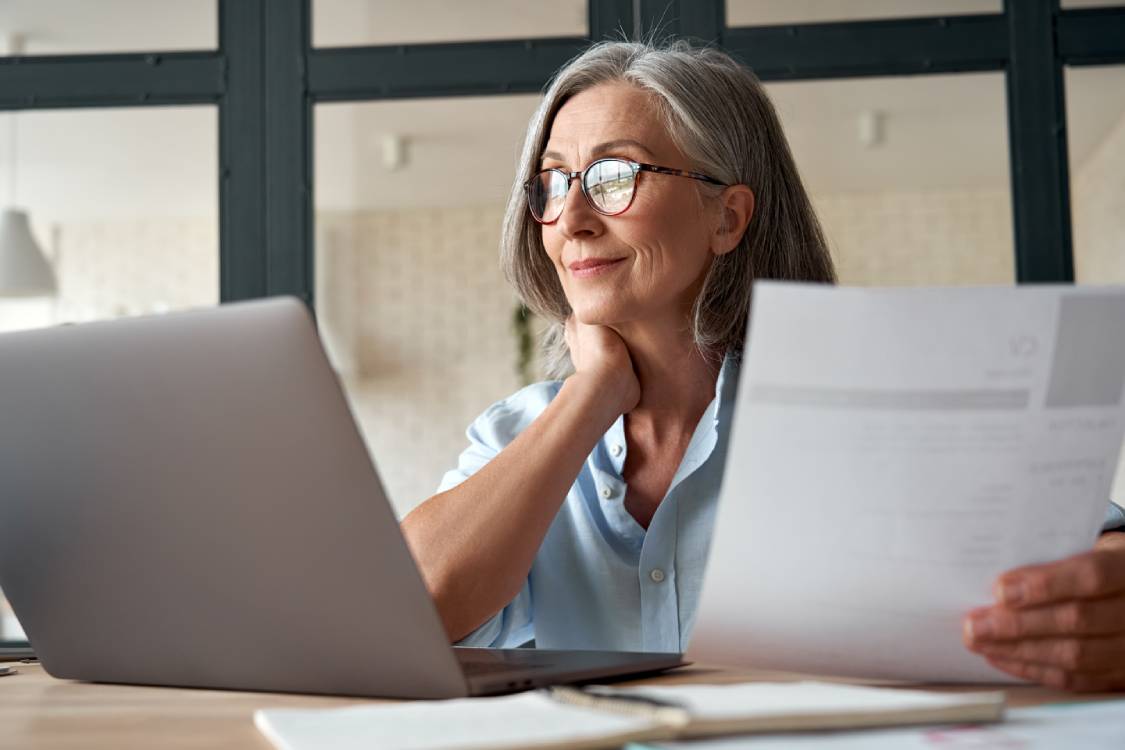 mature woman sitting in front of a laptop looking at her taxes