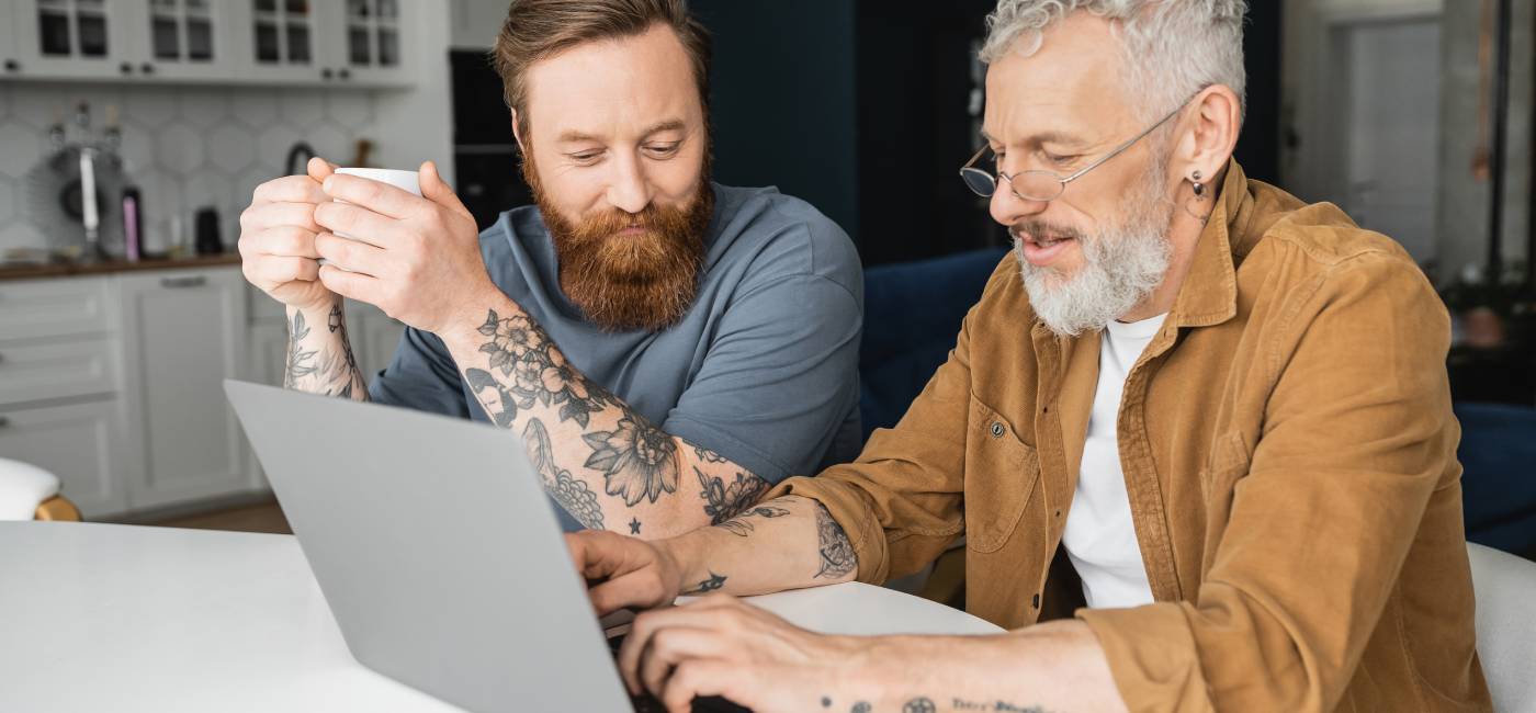 Tattooed couple with coffee using laptop to look at their finances