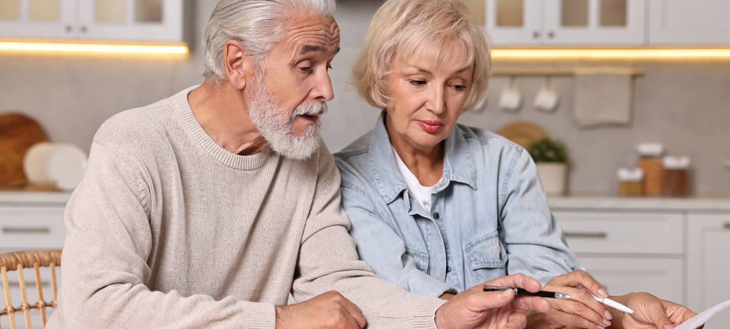 Pension savings. Senior couple planning budget at wooden table indoors