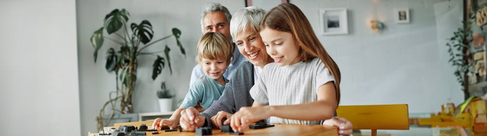 Grandparents sitting with their grandchildren smiling playing board games together