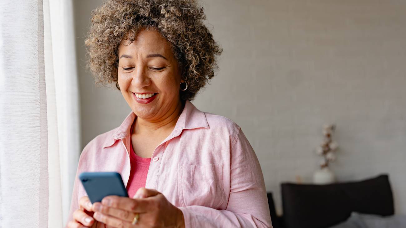 A mature woman standing scrolling through her phone