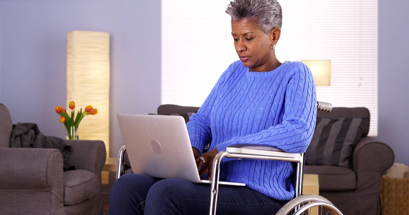 Mature Black woman sitting in wheelchair with laptop