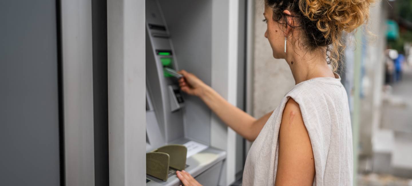 woman using credit card and withdrawing cash at the ATM