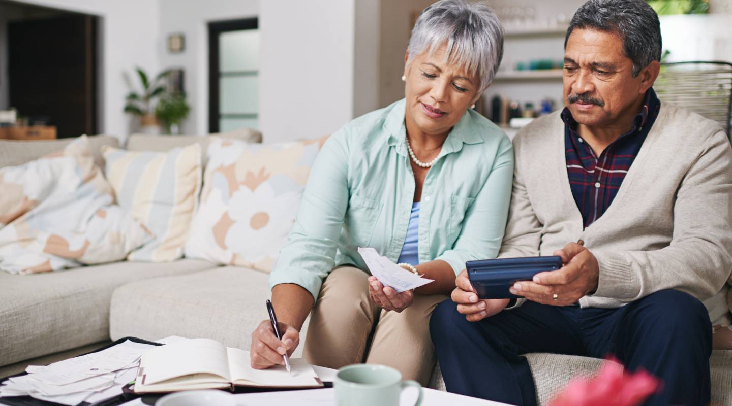 mature Husband and wife working out a budget while sitting on the living room sofa.