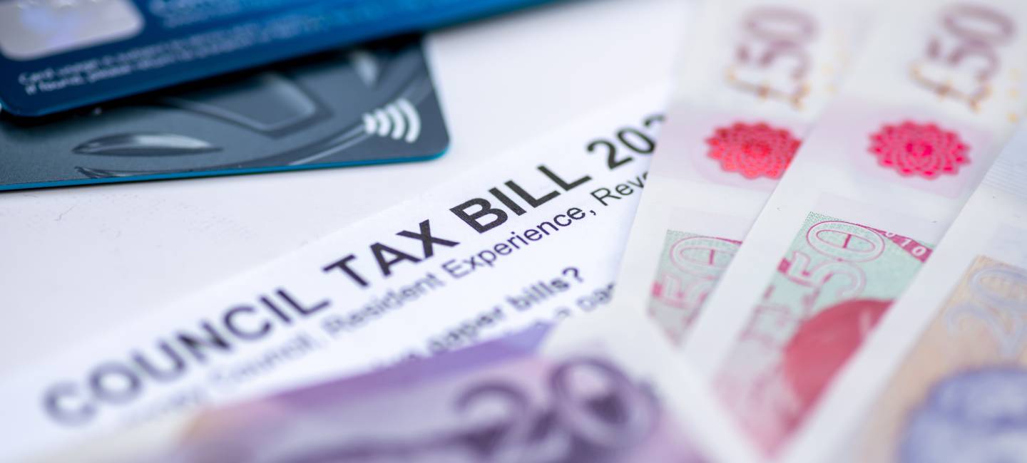 A Council Tax Bill in between Pound Sterling bank notes and bank payment cards