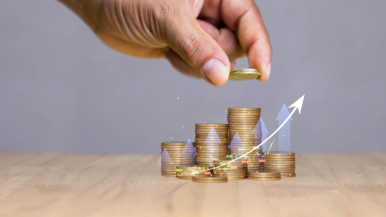 A hand putting gold coins in piles of gold saving money for future and retirement concept. money invest, Save money with stacking coin for growing your business investment.