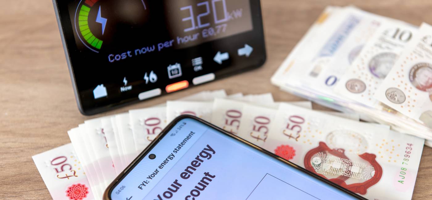 A energy use and cost concept with a digital bill on a mobile phone, a smart energy meter and bank notes.