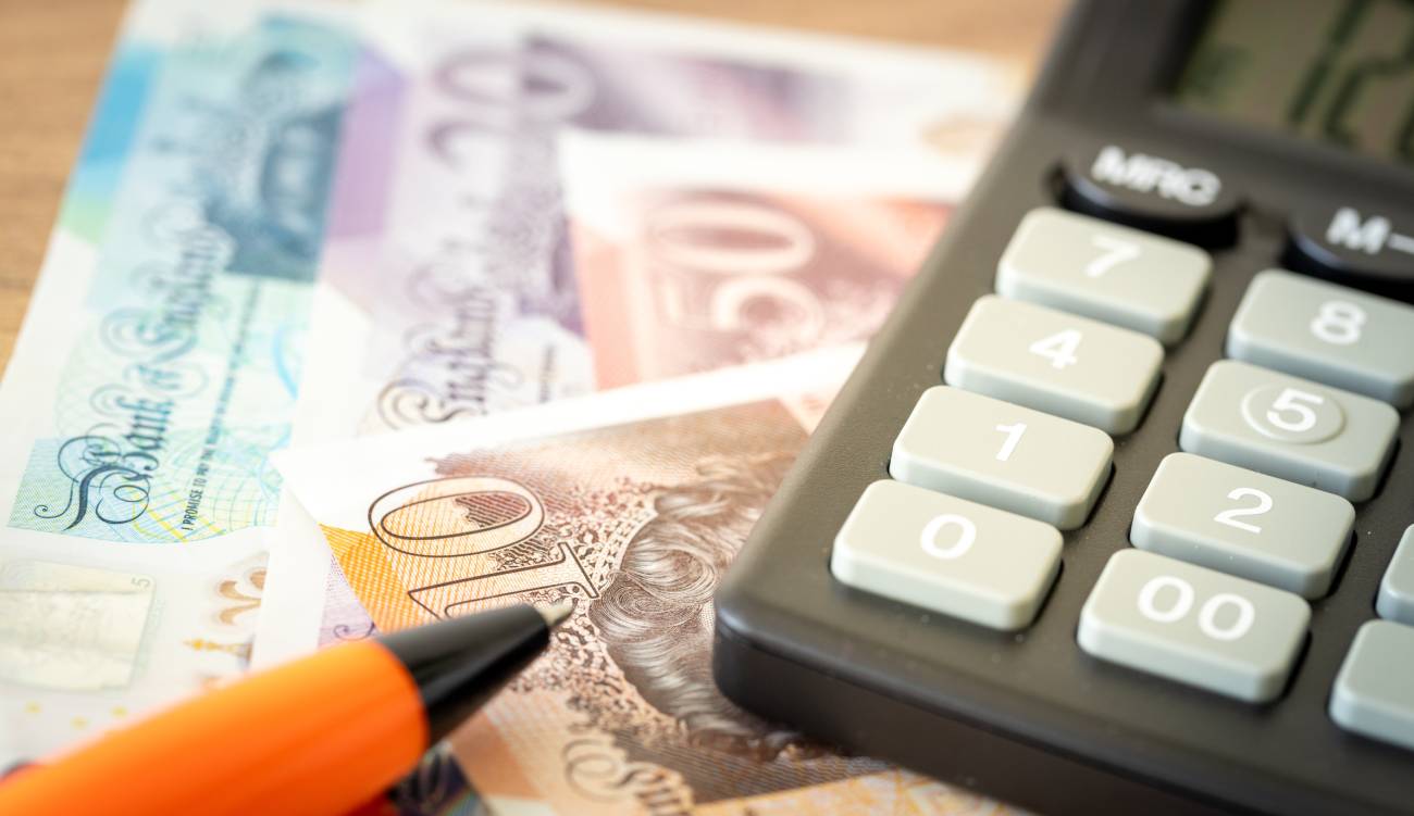 British Pounds, Calculator and Money File on a table with an orange pen