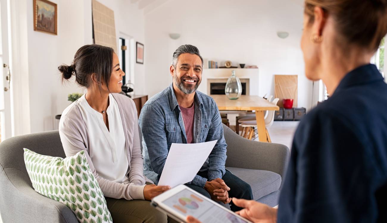 Happy mature couple discussing investments with financial broker during meeting at home. Middle eastern man and woman discussing about financial planning with consultant at home. 