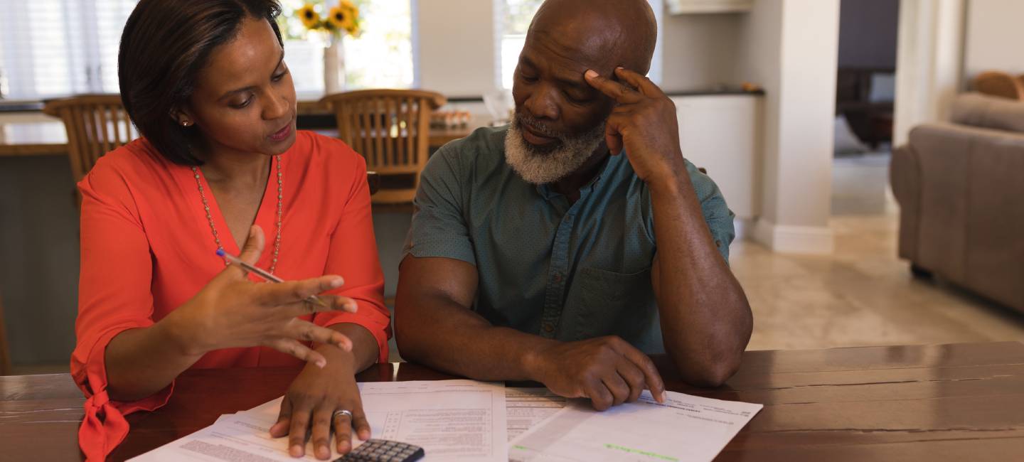 Front view of an active senior couple discussing over savings in the living room at home