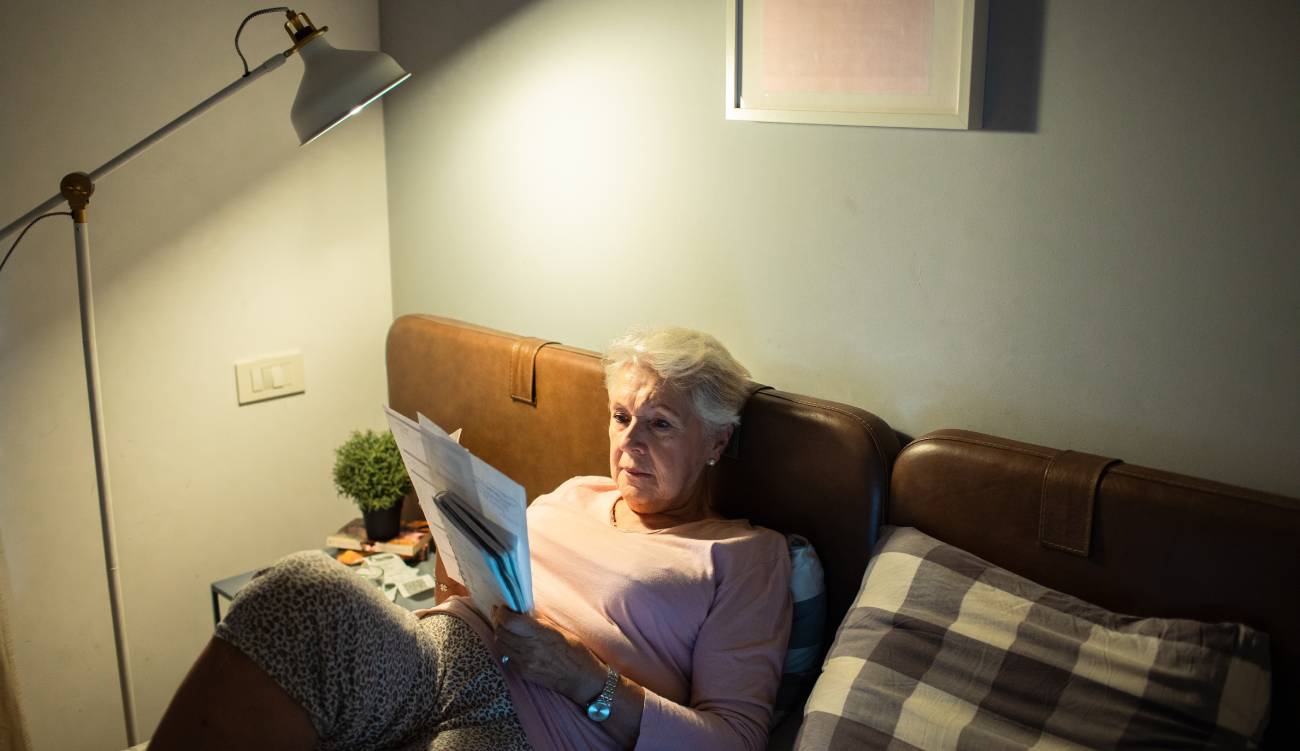 Senior woman reading bills in bed at home