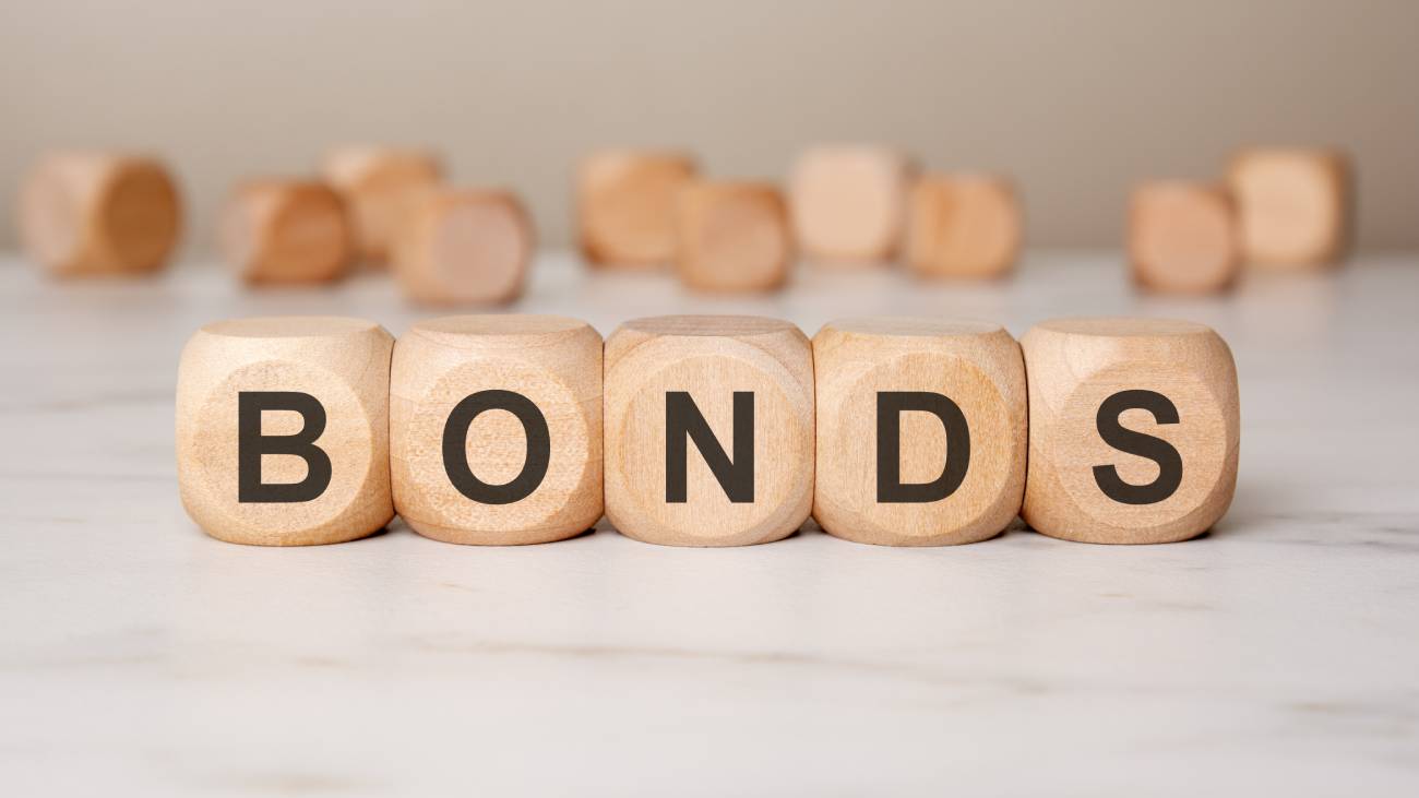 close-up of wooden cubes spelling BONDS on a white surface, with blurred cubes in the background. a symbolic representation of financial markets, investments, and securities trading
