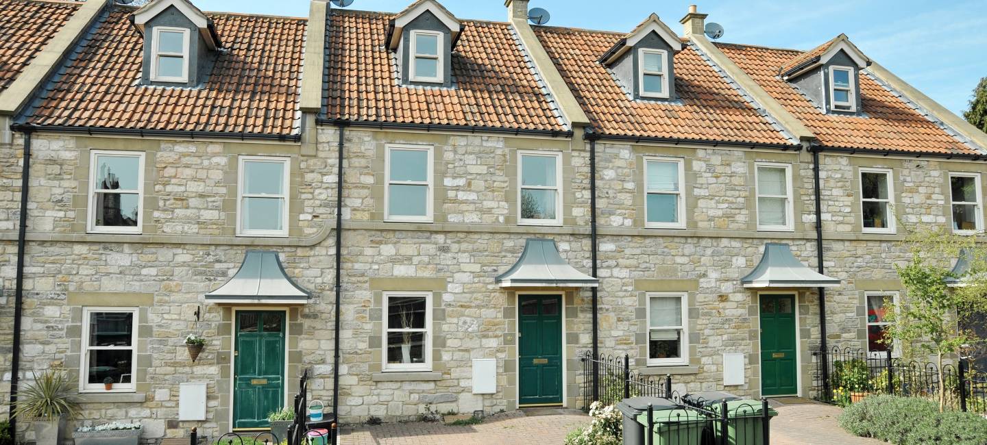 Exterior view of beautiful old terraced stone cottage houses on a street in a typical English town 