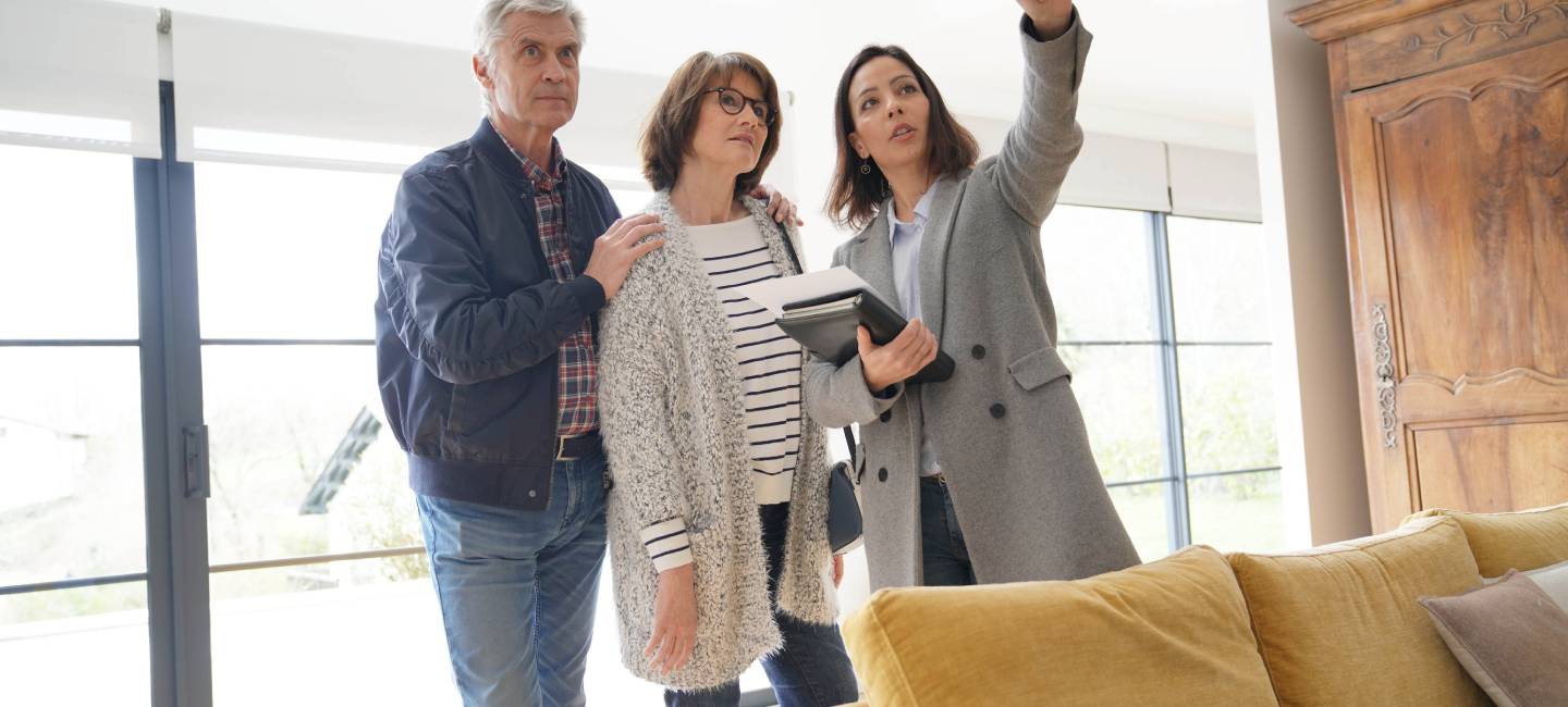 Senior couple with real estate agent visiting contemporary house
