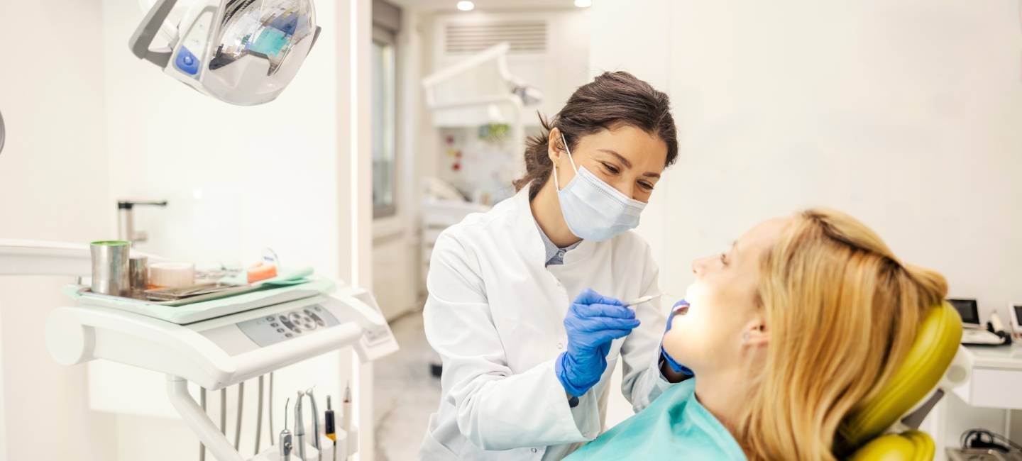 Friendly dentist examining patient's teeth at dentist office.