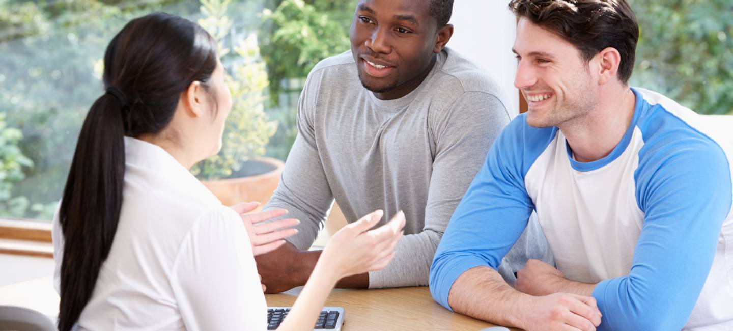 Male Couple Talking With Financial Advisor In Office