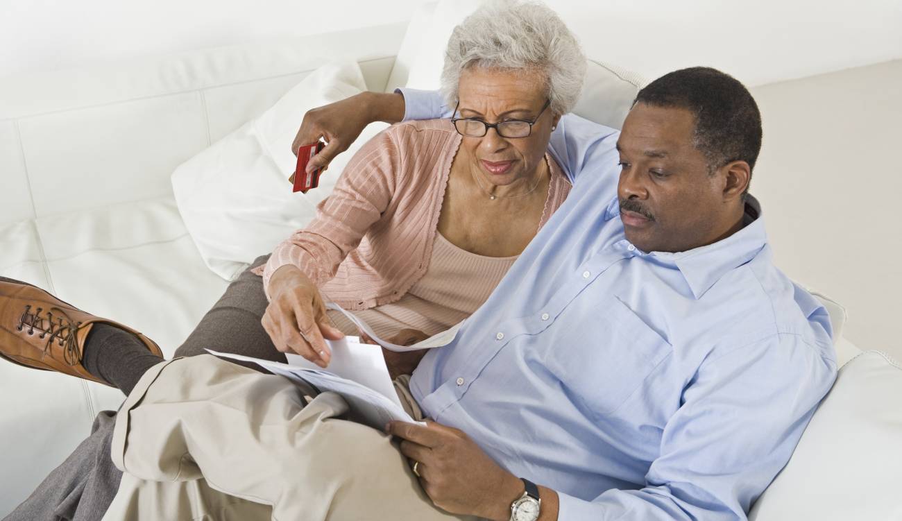 High angle view of senior African American couple looking at bills while sitting on sofa