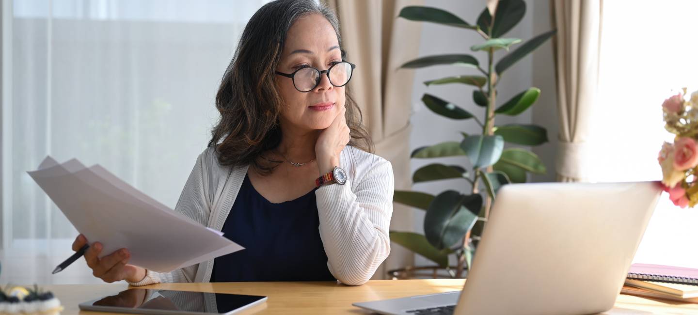 Concentrated older mature woman watching webinar or working online on computer laptop at home