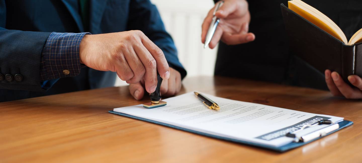 A lawyer or businessman is stamping on a contract document.