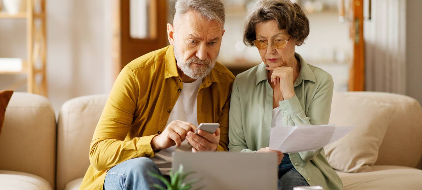 Focused senior spouses using laptop to manage finances